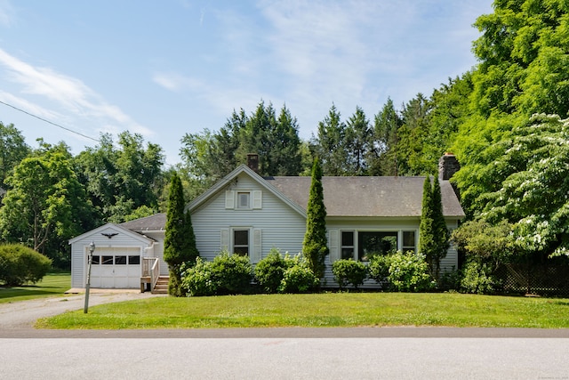 view of front of home featuring a garage, an outdoor structure, and a front lawn