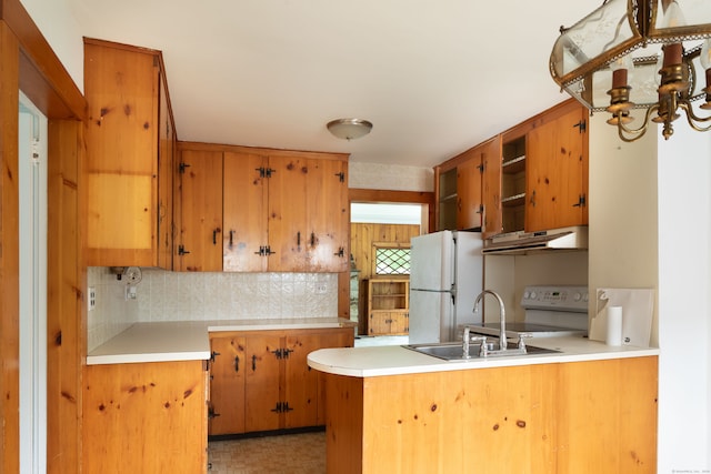 kitchen featuring kitchen peninsula, white appliances, sink, backsplash, and an inviting chandelier