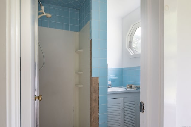 bathroom featuring vanity, tile walls, and a tile shower