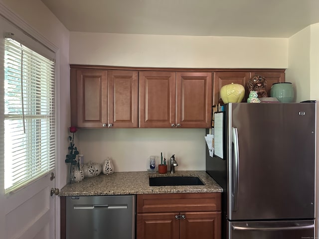 kitchen featuring stainless steel appliances, stone counters, and sink