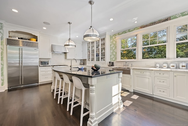147 Old Church Rd, Greenwich, CT 06830 - kitchen with stainless steel built in refrigerator, wall chimney range hood, white cabinets, dark wood finished floors, and recessed lighting