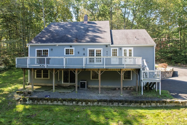 rear view of house with a wooden deck and a lawn