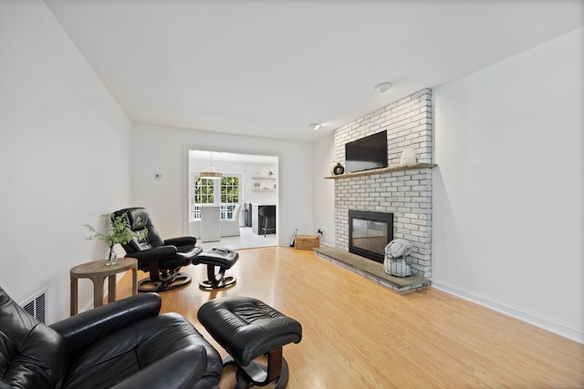 living room with wood-type flooring and a brick fireplace