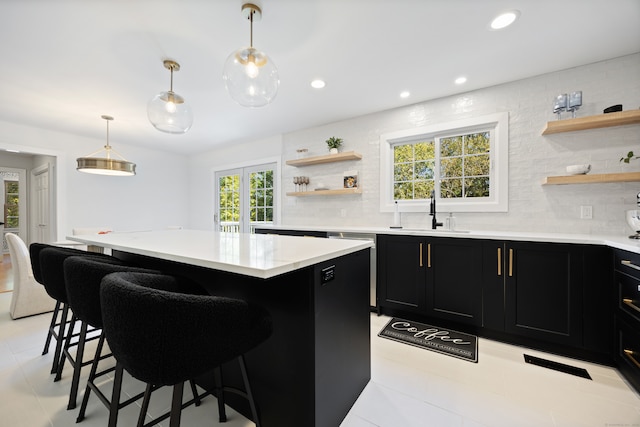 kitchen with pendant lighting, a kitchen breakfast bar, sink, and a center island