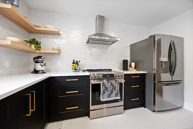 kitchen featuring light stone counters, backsplash, light tile patterned floors, stainless steel appliances, and wall chimney range hood