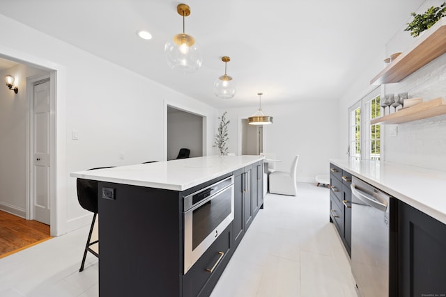 kitchen featuring a center island, a breakfast bar area, decorative backsplash, appliances with stainless steel finishes, and decorative light fixtures