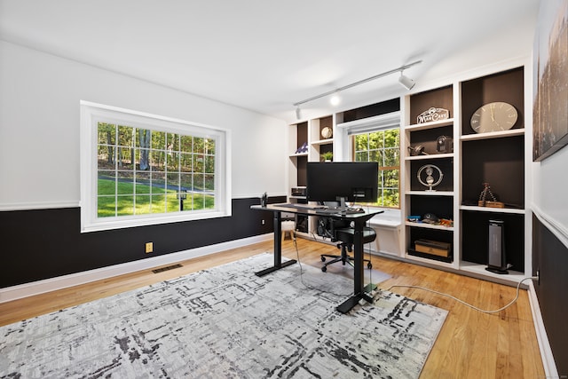 office featuring a healthy amount of sunlight, hardwood / wood-style floors, and track lighting