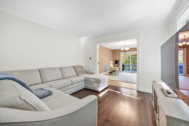 living room featuring a healthy amount of sunlight, ornamental molding, dark hardwood / wood-style floors, and a notable chandelier