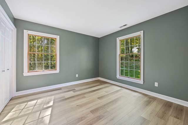 empty room with light hardwood / wood-style flooring and plenty of natural light