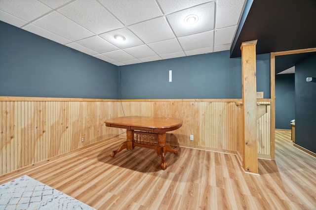 dining room featuring a drop ceiling, wood walls, and hardwood / wood-style flooring