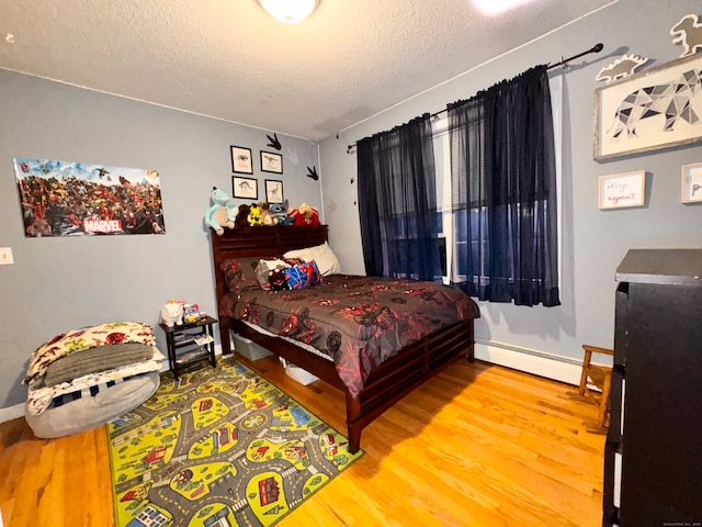 bedroom with wood-type flooring, a textured ceiling, and a baseboard heating unit