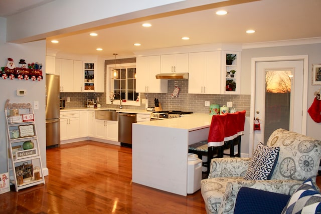 kitchen with backsplash, sink, hanging light fixtures, white cabinetry, and stainless steel appliances