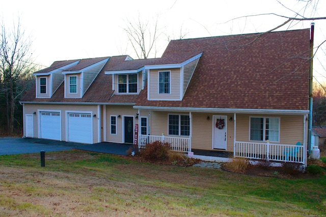 view of front facade featuring covered porch, a garage, and a front lawn