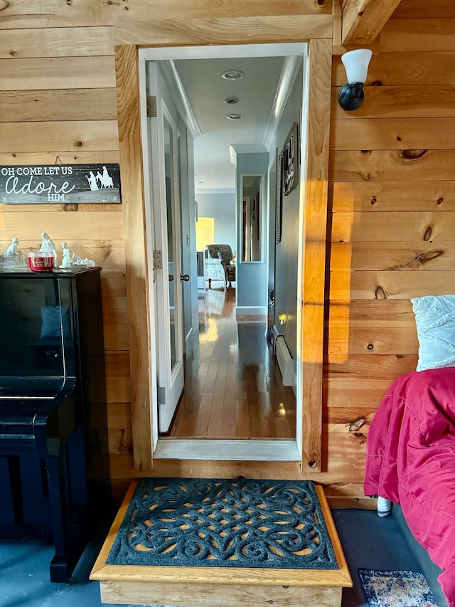 hall featuring dark hardwood / wood-style flooring, wooden walls, and a baseboard radiator