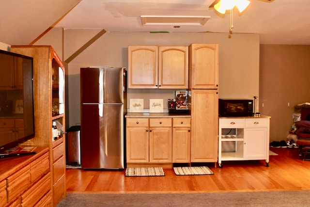 kitchen featuring light brown cabinets, light hardwood / wood-style floors, stainless steel refrigerator, and ceiling fan