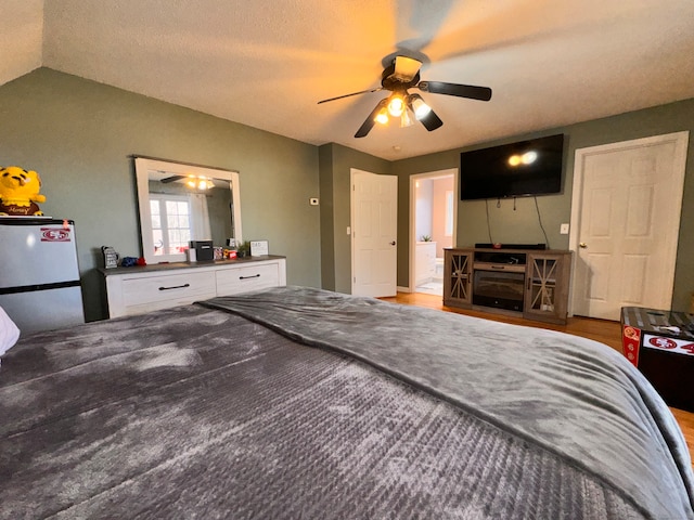 bedroom with lofted ceiling, hardwood / wood-style flooring, ceiling fan, a textured ceiling, and white fridge