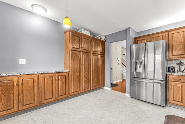 kitchen featuring decorative light fixtures, light stone countertops, and stainless steel fridge