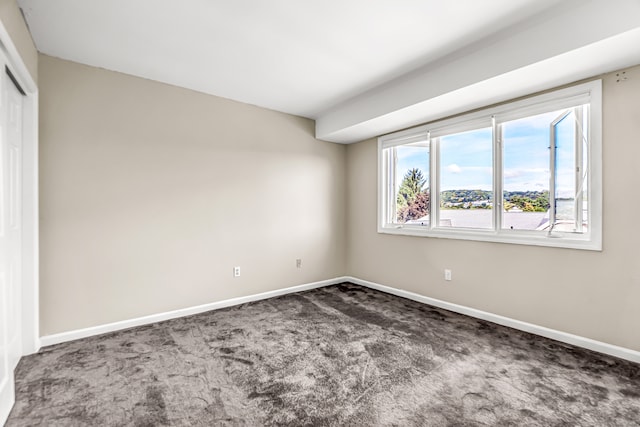 unfurnished room featuring dark colored carpet