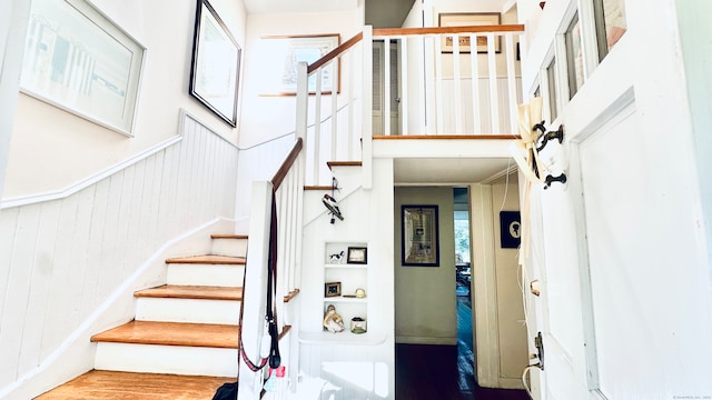 stairway with wood walls and hardwood / wood-style flooring