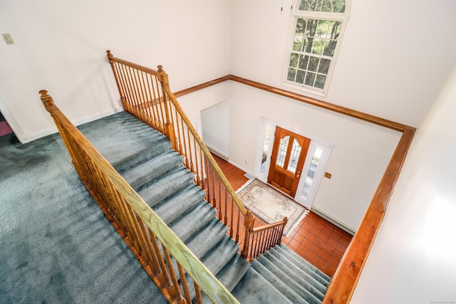 carpeted foyer featuring a high ceiling and a baseboard radiator