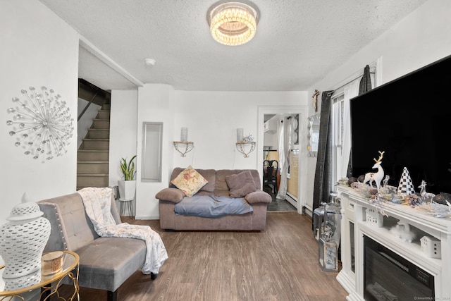 living room featuring wood-type flooring, a textured ceiling, and baseboard heating