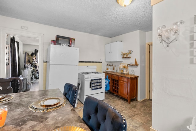 kitchen with white cabinets, a textured ceiling, and white appliances