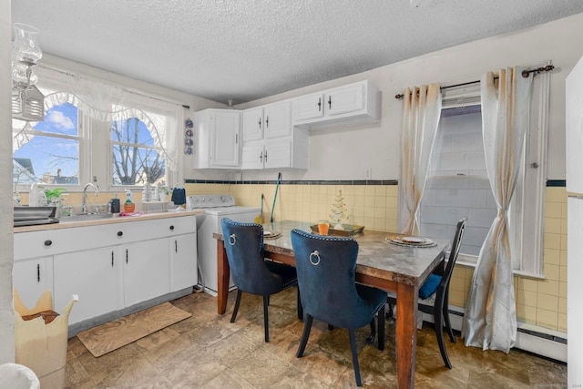 dining room featuring washer / clothes dryer, a textured ceiling, tile walls, and sink