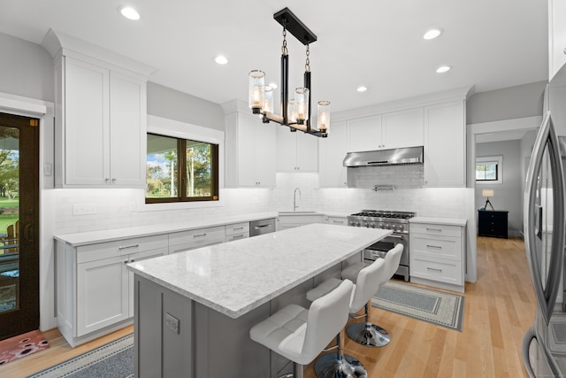 kitchen with appliances with stainless steel finishes, light wood-type flooring, white cabinetry, and a kitchen island