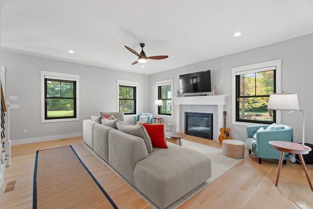 living room featuring ceiling fan, plenty of natural light, and light hardwood / wood-style floors