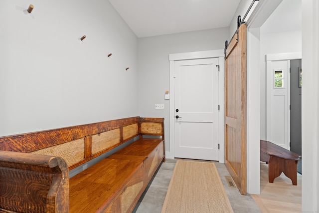 mudroom with a barn door and light hardwood / wood-style flooring