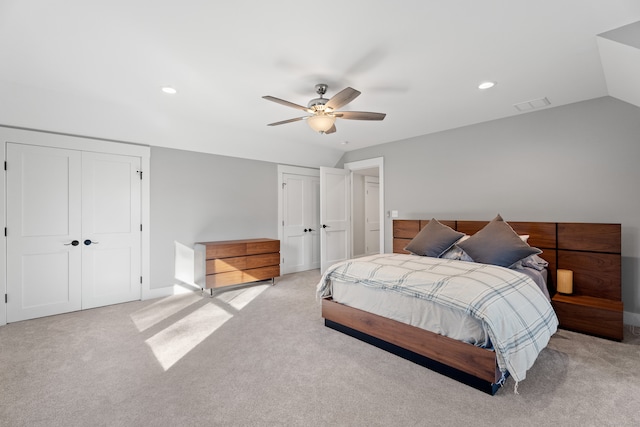 carpeted bedroom with vaulted ceiling, ceiling fan, and multiple closets