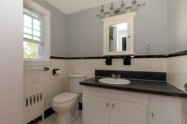 161 Dale Rd, Wethersfield, CT 06109 - bathroom with radiator heating unit, vanity, wainscoting, tile walls, and tile patterned floors
