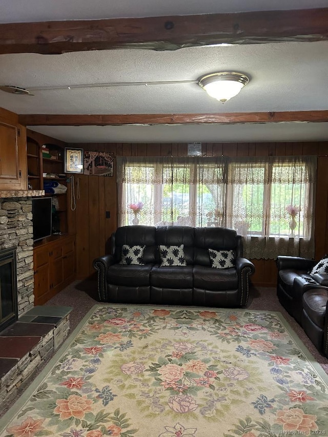 carpeted living room featuring a textured ceiling, a healthy amount of sunlight, and a stone fireplace