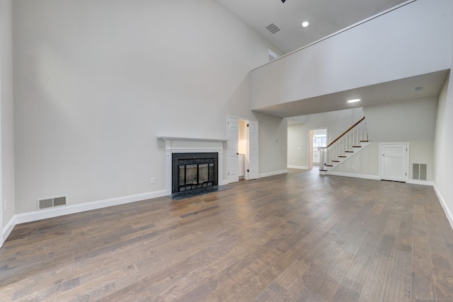 unfurnished living room featuring wood-type flooring and high vaulted ceiling