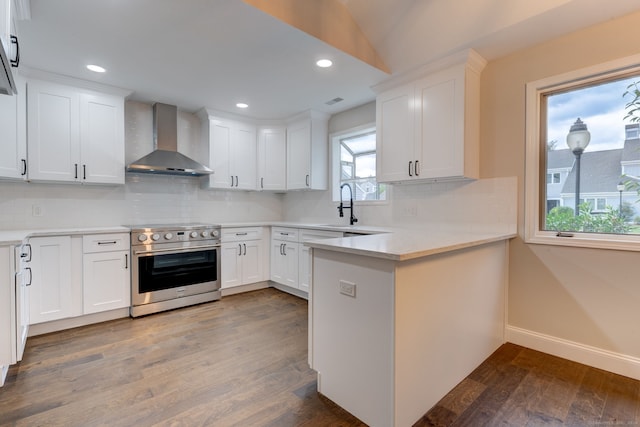 kitchen featuring stainless steel range with electric cooktop, wall chimney exhaust hood, and white cabinetry