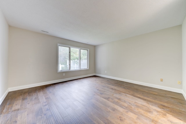 spare room featuring a textured ceiling and hardwood / wood-style floors