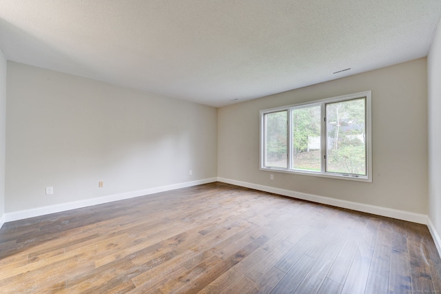 spare room with wood-type flooring and a textured ceiling