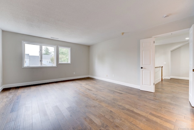 unfurnished room with wood-type flooring and a textured ceiling