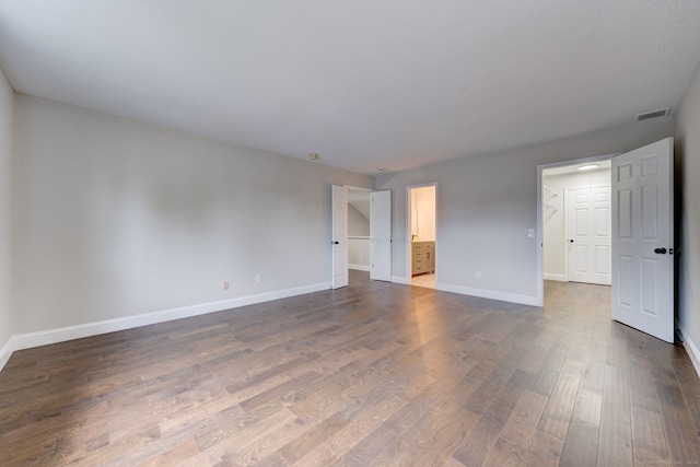 unfurnished bedroom with connected bathroom and dark wood-type flooring