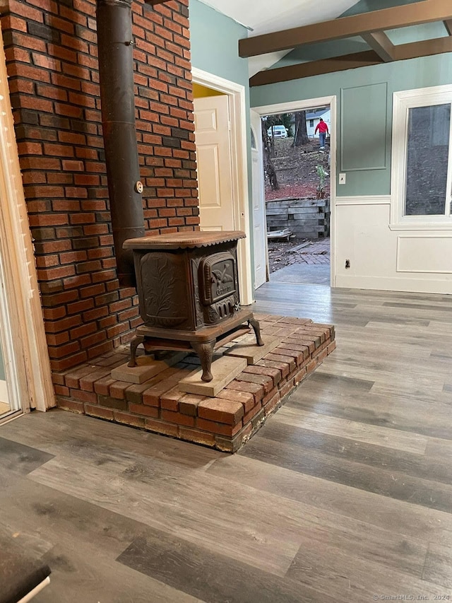 room details featuring beam ceiling, a wood stove, and hardwood / wood-style flooring