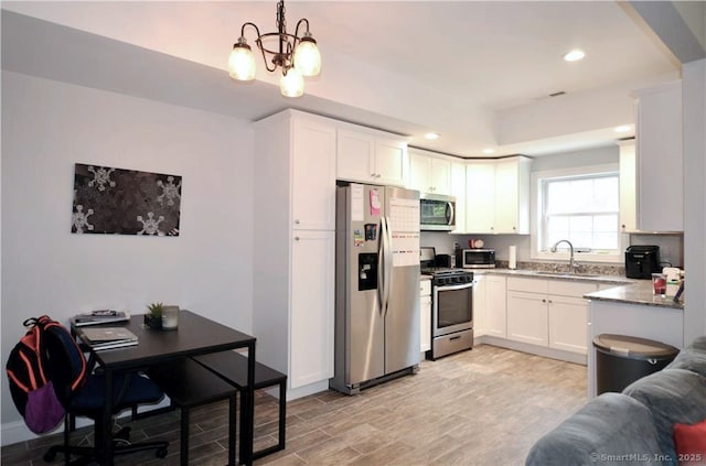 kitchen featuring sink, decorative light fixtures, stainless steel appliances, light hardwood / wood-style floors, and white cabinets