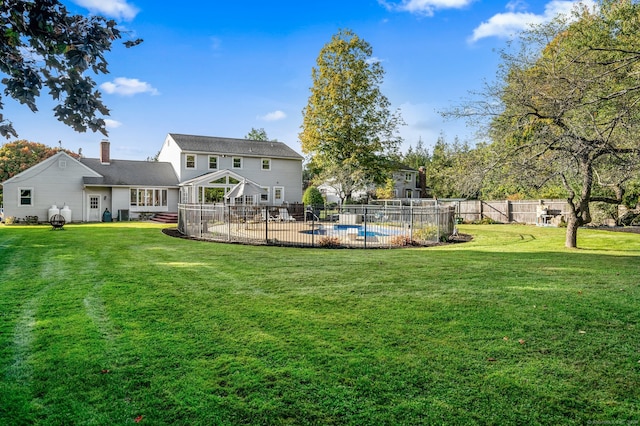 back of house featuring a yard, a fenced in pool, and a patio area