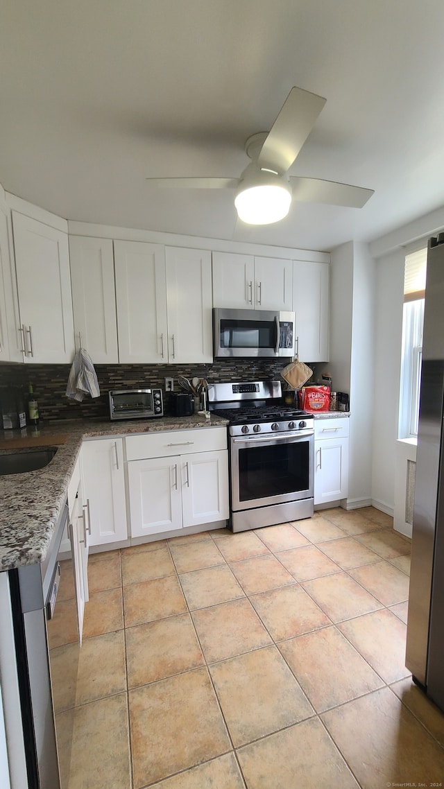 kitchen featuring dark stone counters, white cabinets, appliances with stainless steel finishes, and tasteful backsplash