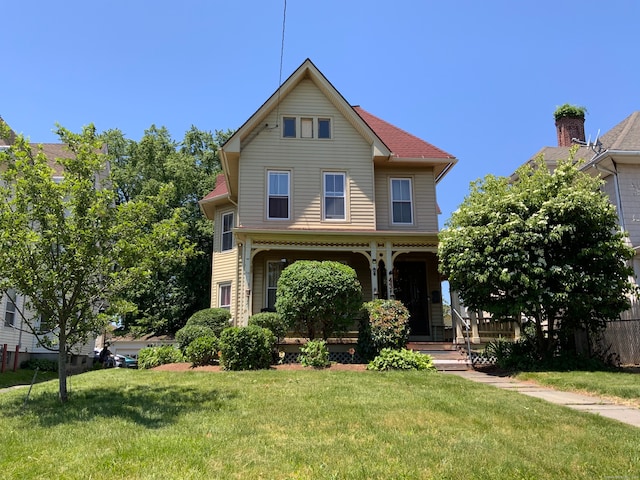 front facade with covered porch and a front yard