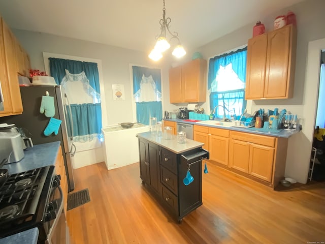 kitchen featuring light hardwood / wood-style floors, light brown cabinets, pendant lighting, stainless steel appliances, and a center island