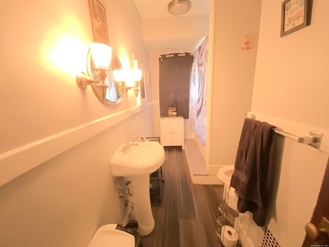 bathroom with a shower with shower curtain, wood-type flooring, and toilet