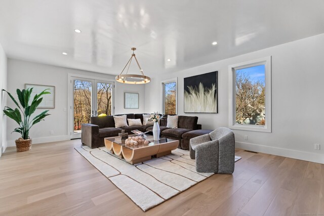 living room featuring light hardwood / wood-style floors, french doors, and a chandelier