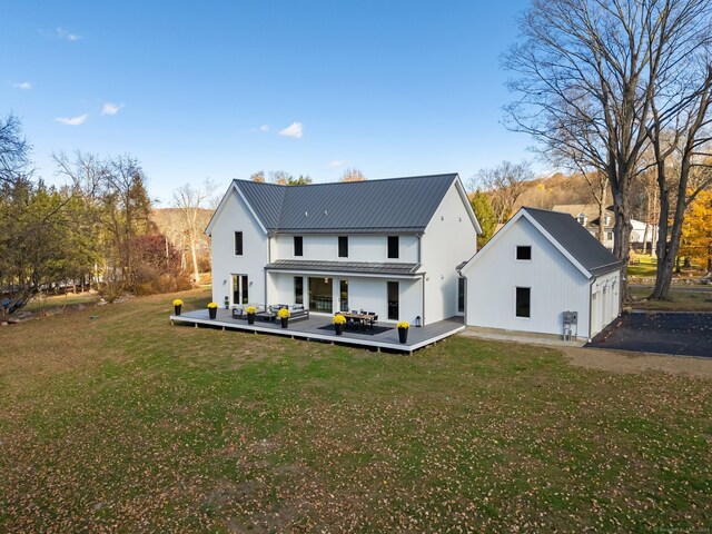 rear view of property with a wooden deck and a lawn