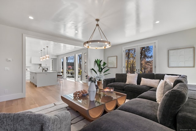 living room featuring a chandelier, french doors, light hardwood / wood-style floors, and sink