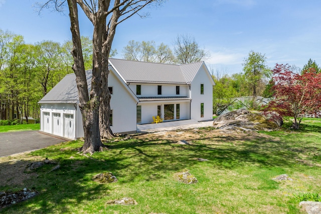 modern farmhouse style home featuring a garage, driveway, metal roof, and a front yard